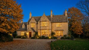 Cotswold stone house at twilight with autumn trees