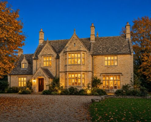 Cotswold stone house at twilight with autumn trees