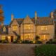 Cotswold stone house at twilight with autumn trees